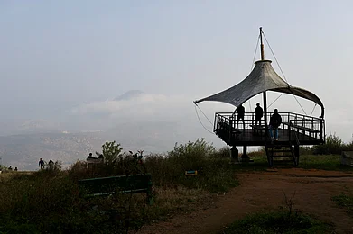 manoj_kulkarni/Shutterstock : People take in the sunrise from a viewpoint at the summit of Nandi Hills